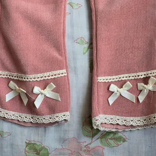 Dusty pink flare pants with lace and bows at the hem